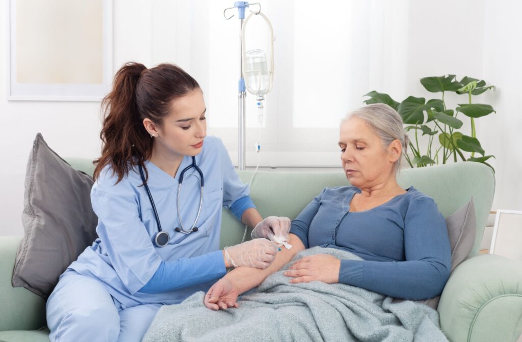 A skilled nurse inserts an IV into an older adult’s arm to provide medical care in their private home residence