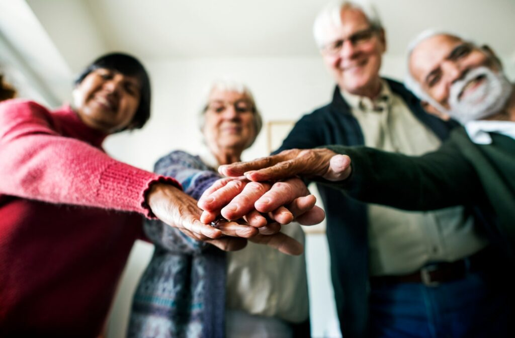 a group of senior putting their hands together in a senior living community