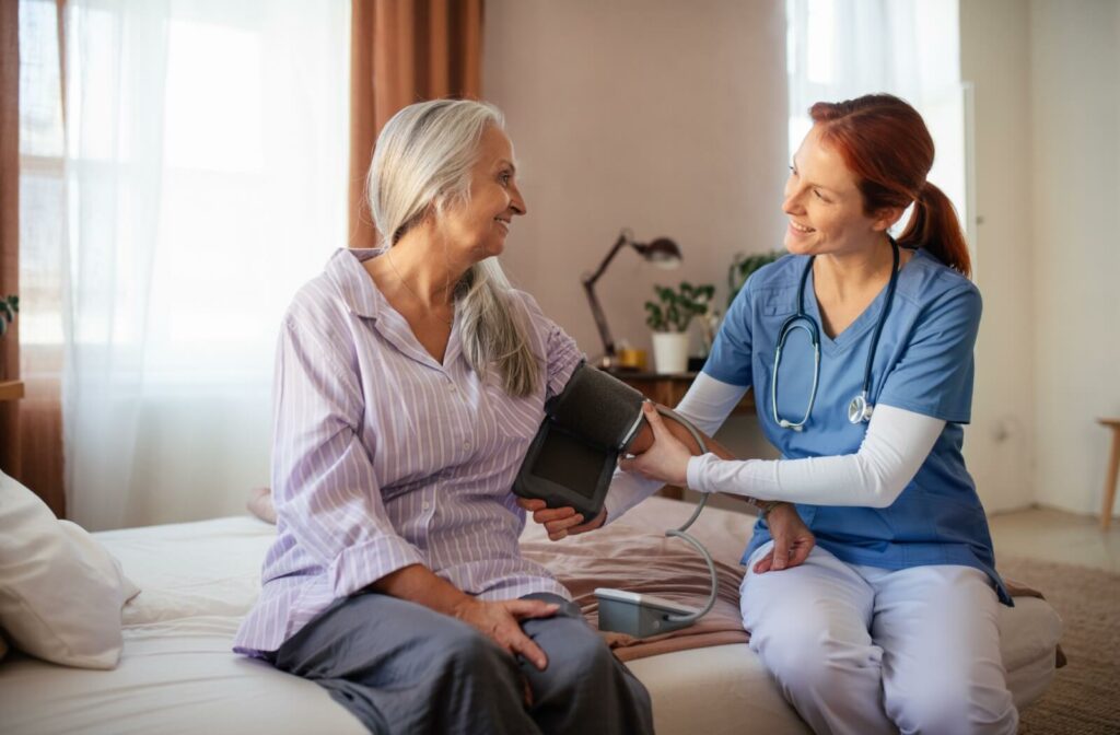 a home health nurse cheking blood pressure of a senior woman